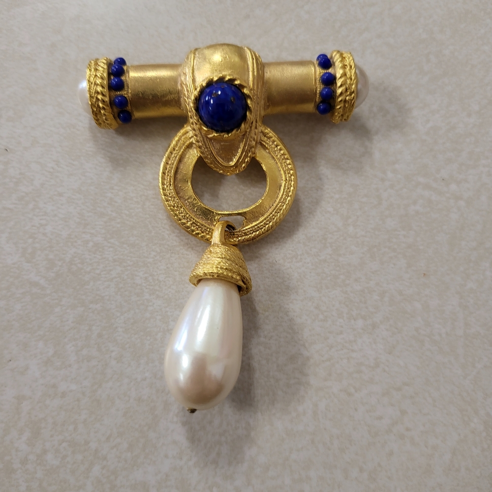 Les Bernard brooch is a vintage piece from the 1980s, featuring gold-toned metal